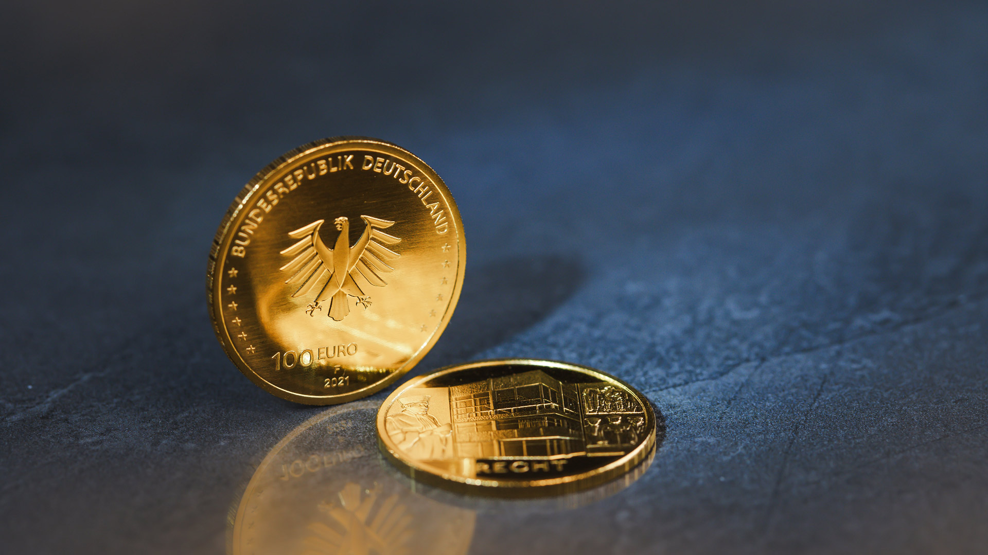 Die 100-Euro-Goldmünze Säulen der Demokratie - Recht steht vor blau-grauen Hintergrund Die 100-Euro-Goldmünze Säulen der Demokratie - Recht steht vor blau-grauen Hintergrund