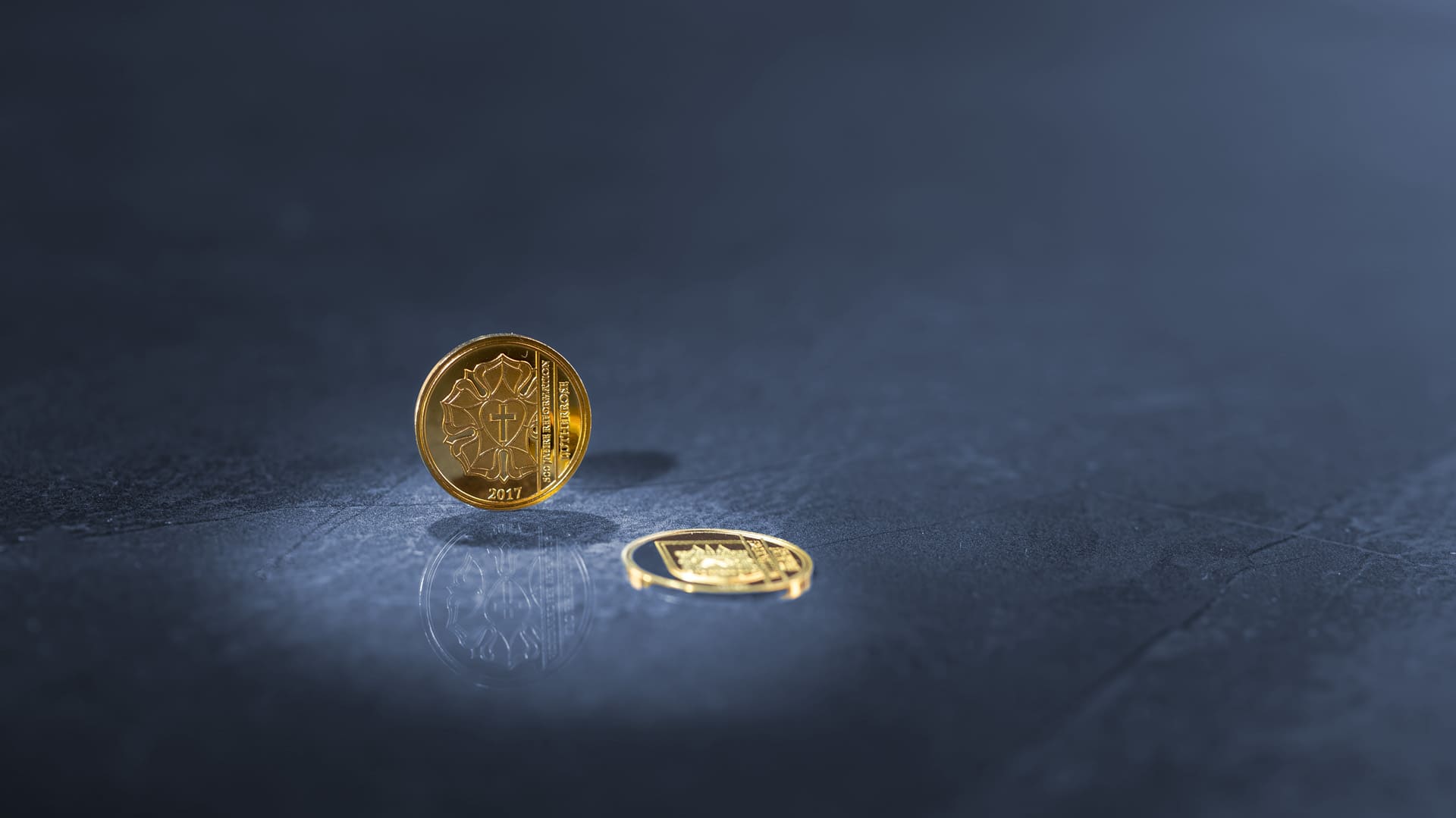 Kleine Goldmünze steht vor blau-grauen Hintergrund Kleine Goldmünze steht vor blau-grauen Hintergrund
