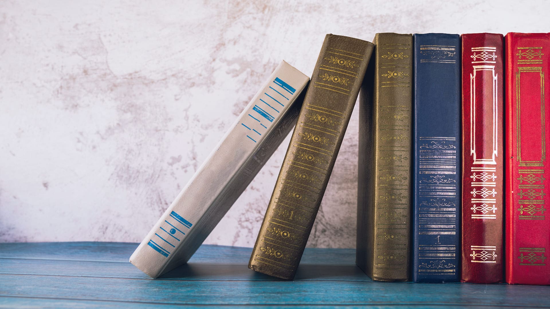 Sechs Bücher stehen in einem Bücherregal nebeneinander Sechs Bücher stehen in einem Bücherregal nebeneinander