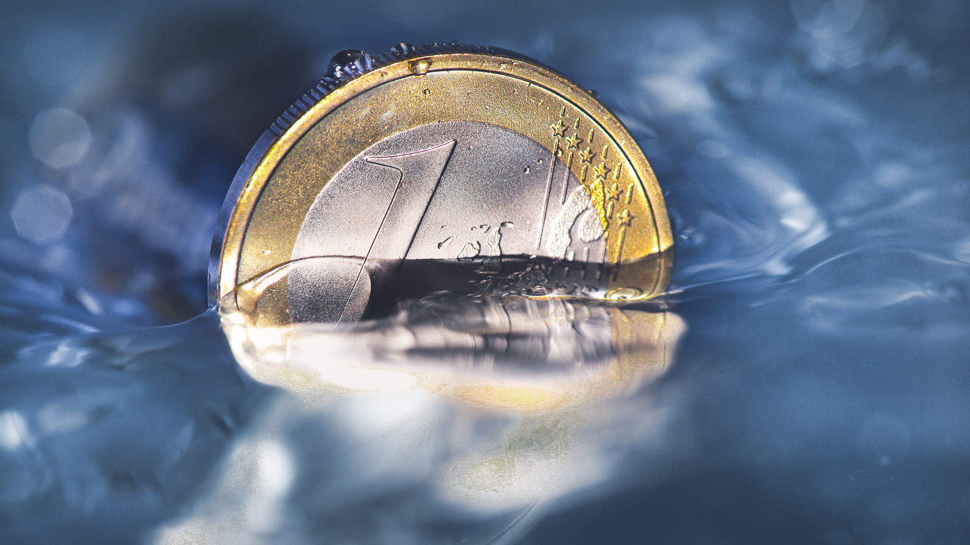 1-Euro-Münze steht zur Hälfte in Flüssigkeit 1-Euro-Münze steht zur Hälfte in Flüssigkeit