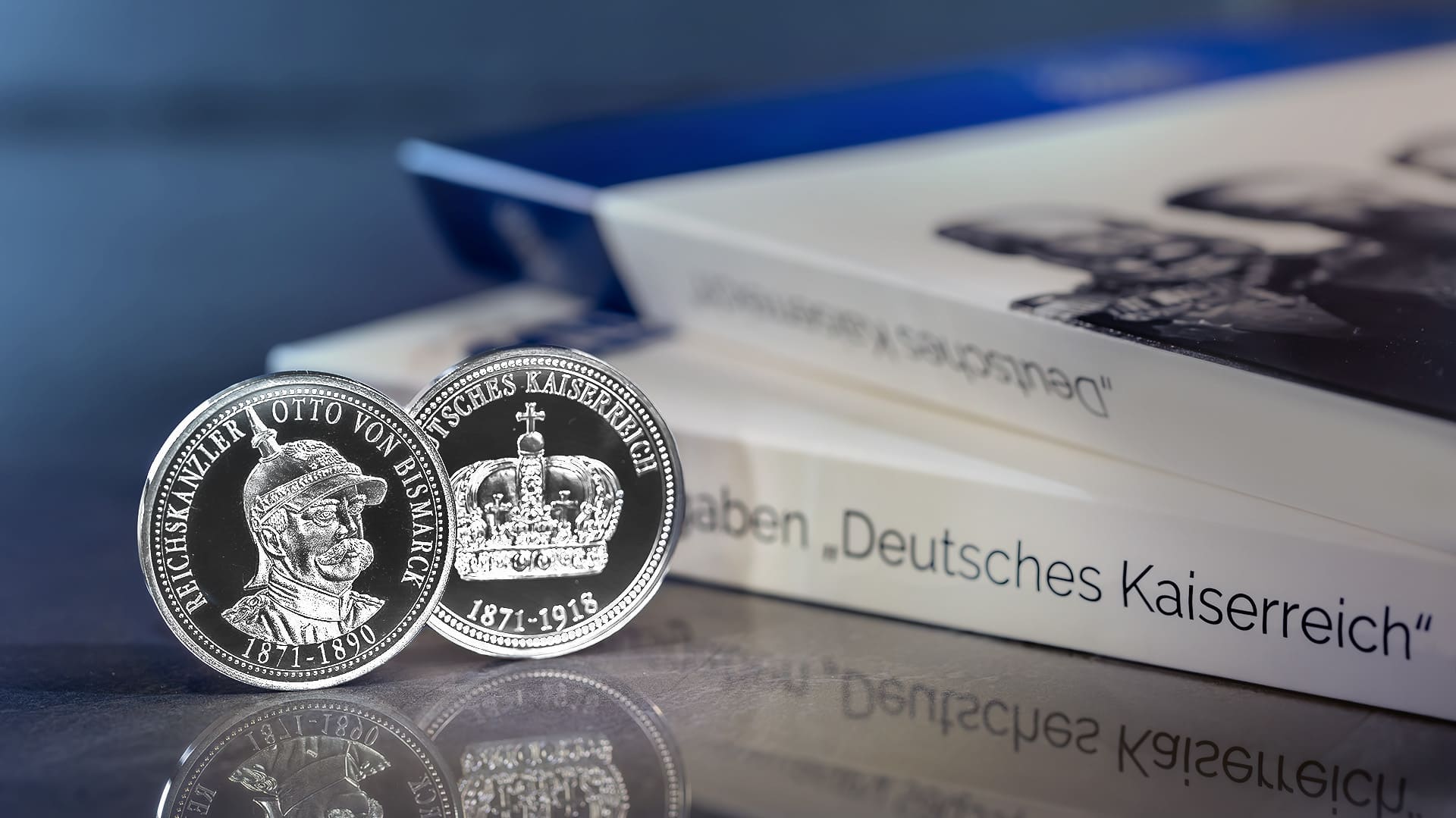 Eine Silber-Gedenkprägung zum Reichskanzler Otto von Bismarck steht neben zwei Sammlermappen zum Deutschen Kaiserreich Eine Silber-Gedenkprägung zum Reichskanzler Otto von Bismarck steht neben zwei Sammlermappen zum Deutschen Kaiserreich