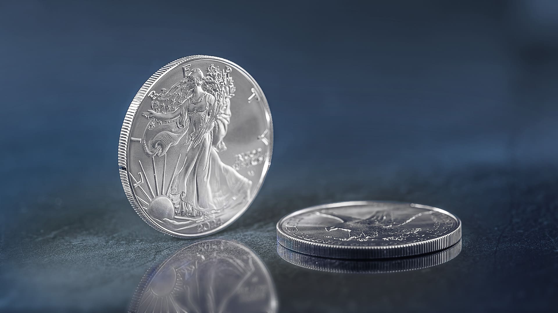 Silbermünze Silver Eagle aus 2023 steht vor blau-grauem Hintergrund Silbermünze Silver Eagle aus 2023 steht vor blau-grauem Hintergrund