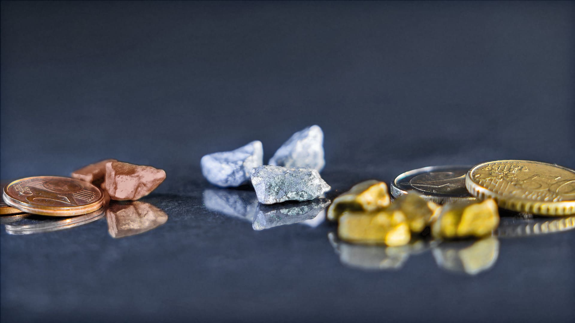 Verschiedene Rohstoffe von Münzmaterialen liegen auf blau-grauen Hintergrund Verschiedene Rohstoffe von Münzmaterialen liegen auf blau-grauen Hintergrund