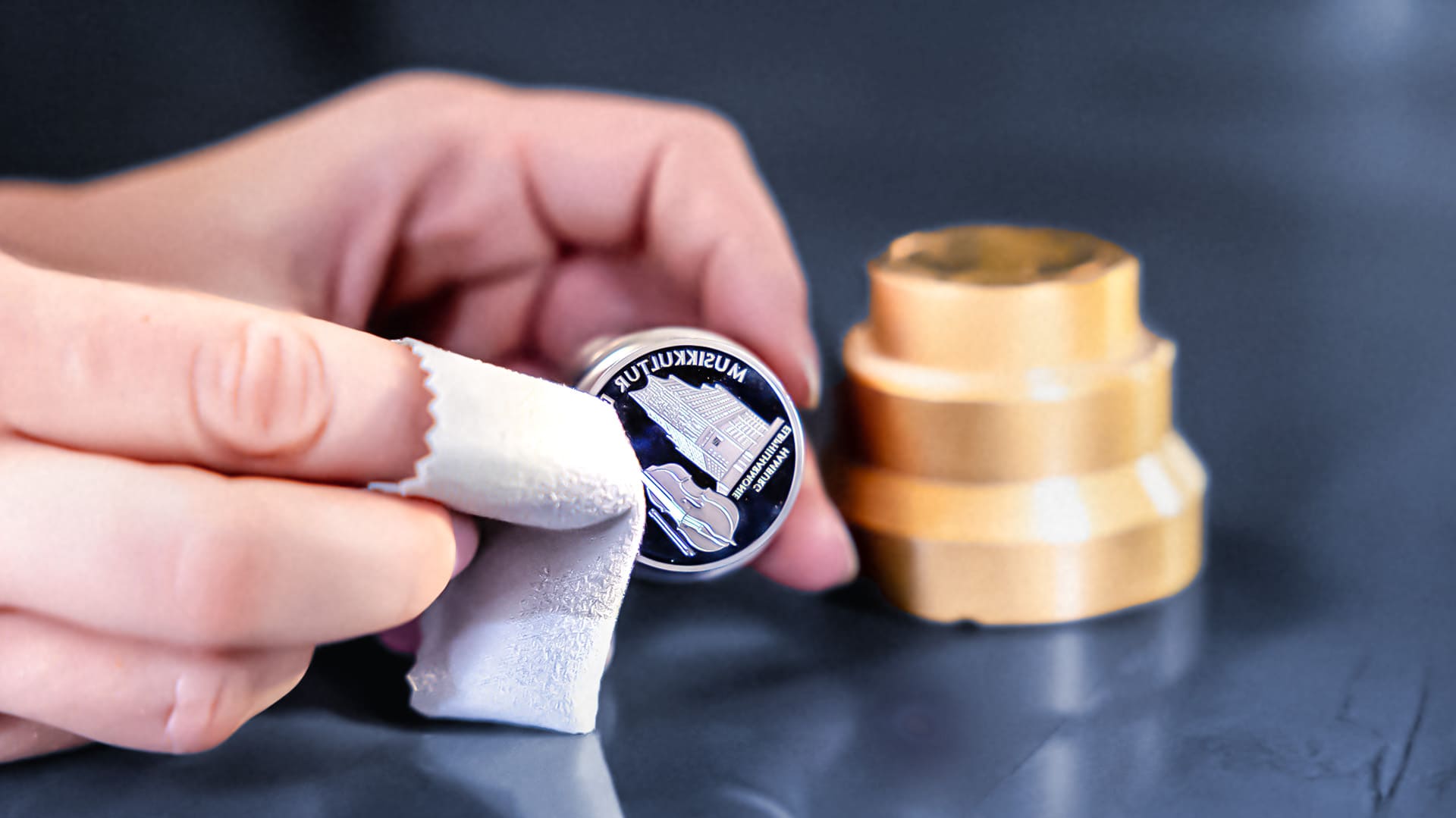 Hand hält Stempel in der Hand, während die andere Hand, mit Poliertuch über den Zeigefinger, den Stempel poliert Hand hält Stempel in der Hand, während die andere Hand, mit Poliertuch über den Zeigefinger, den Stempel poliert
