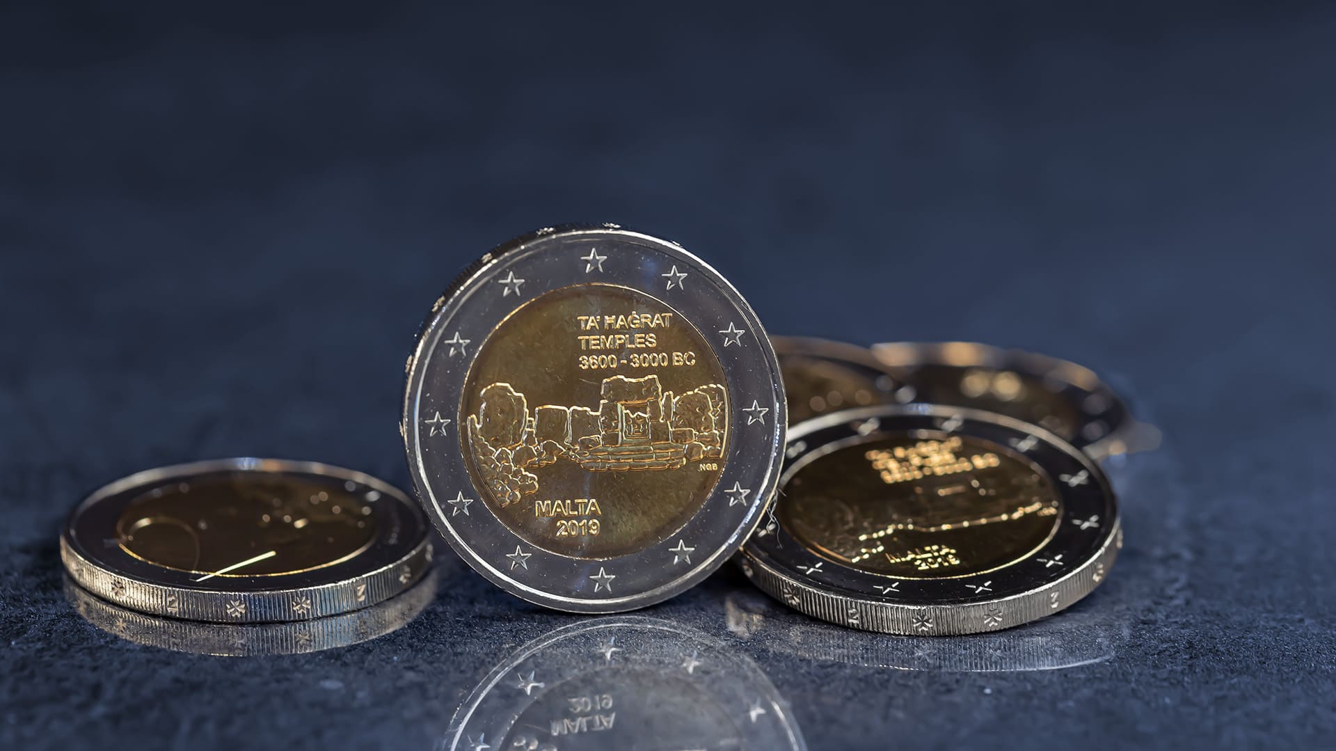 Eine 2-Euro-Münze aus Malta steht vor blau-grauen Hintergrund Eine 2-Euro-Münze aus Malta steht vor blau-grauen Hintergrund