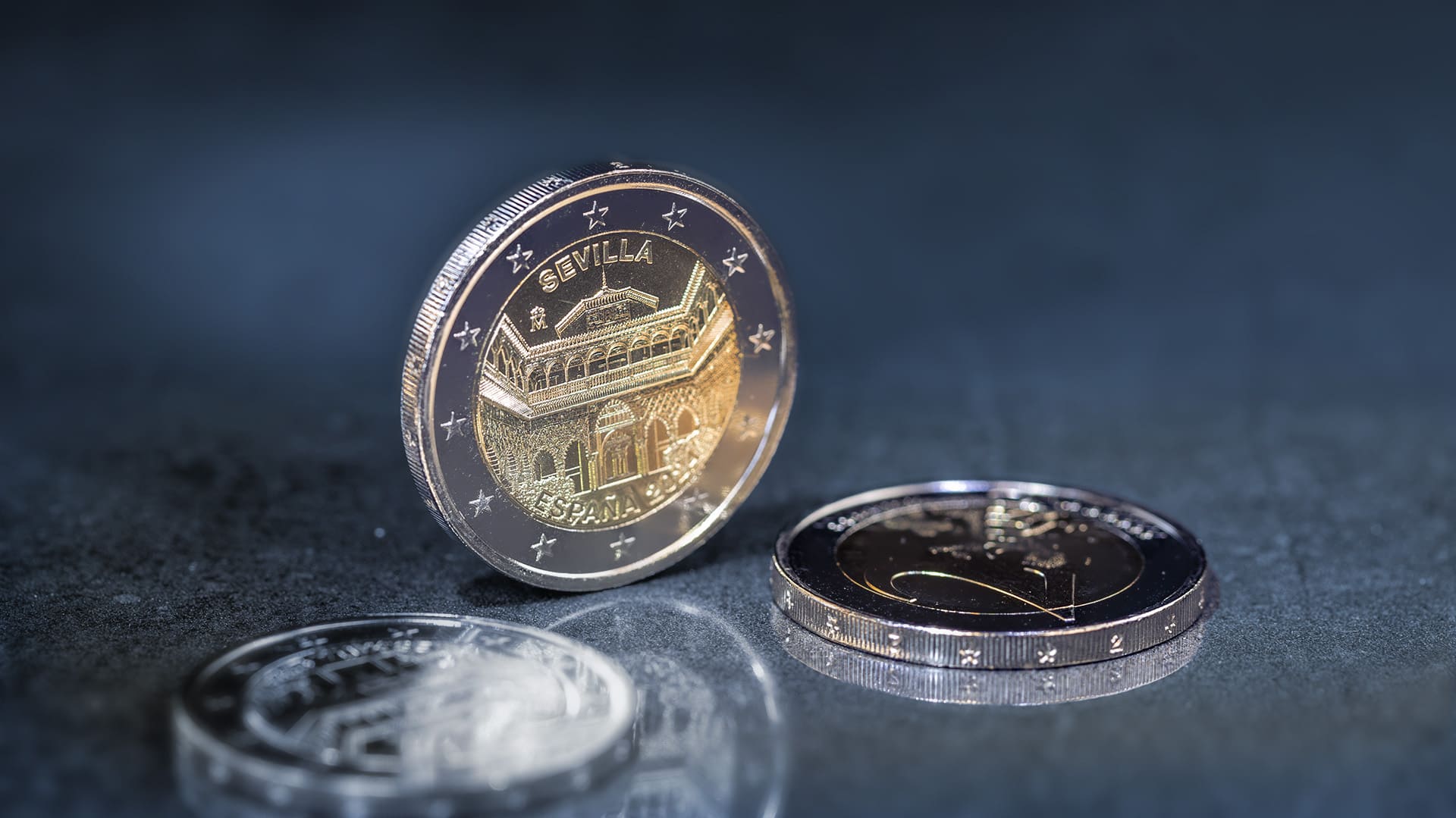 Eine spanische 2-Euro-Münze steht vor blau-grauen Hintergrund Eine spanische 2-Euro-Münze steht vor blau-grauen Hintergrund