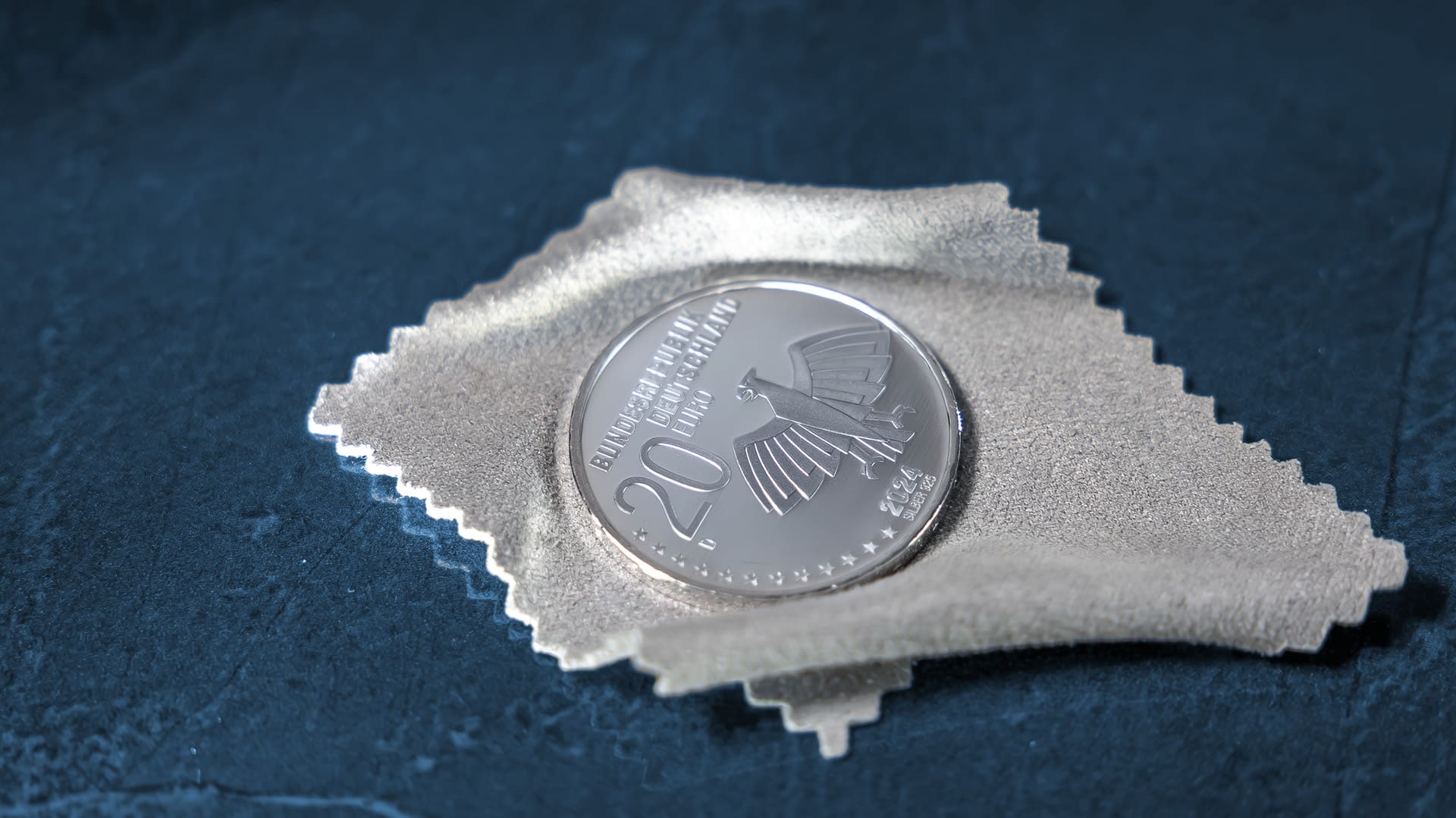 Münze liegt auf einen kleinen grauen Tuch auf blau-grauen Hintergrund Münze liegt auf einen kleinen grauen Tuch auf blau-grauen Hintergrund