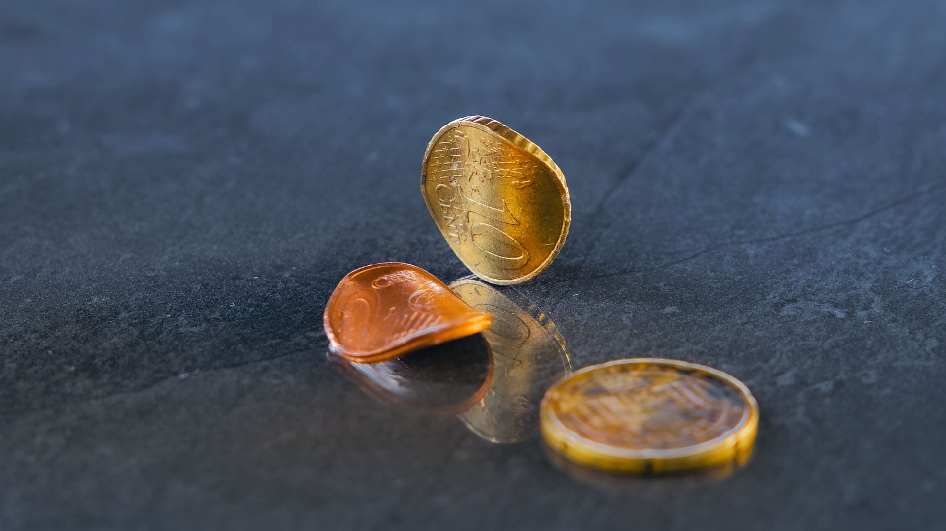 Verbogene Euro-Kursmünzen auf einem dunklen Hintergrund Verbogene Euro-Kursmünzen auf einem dunklen Hintergrund