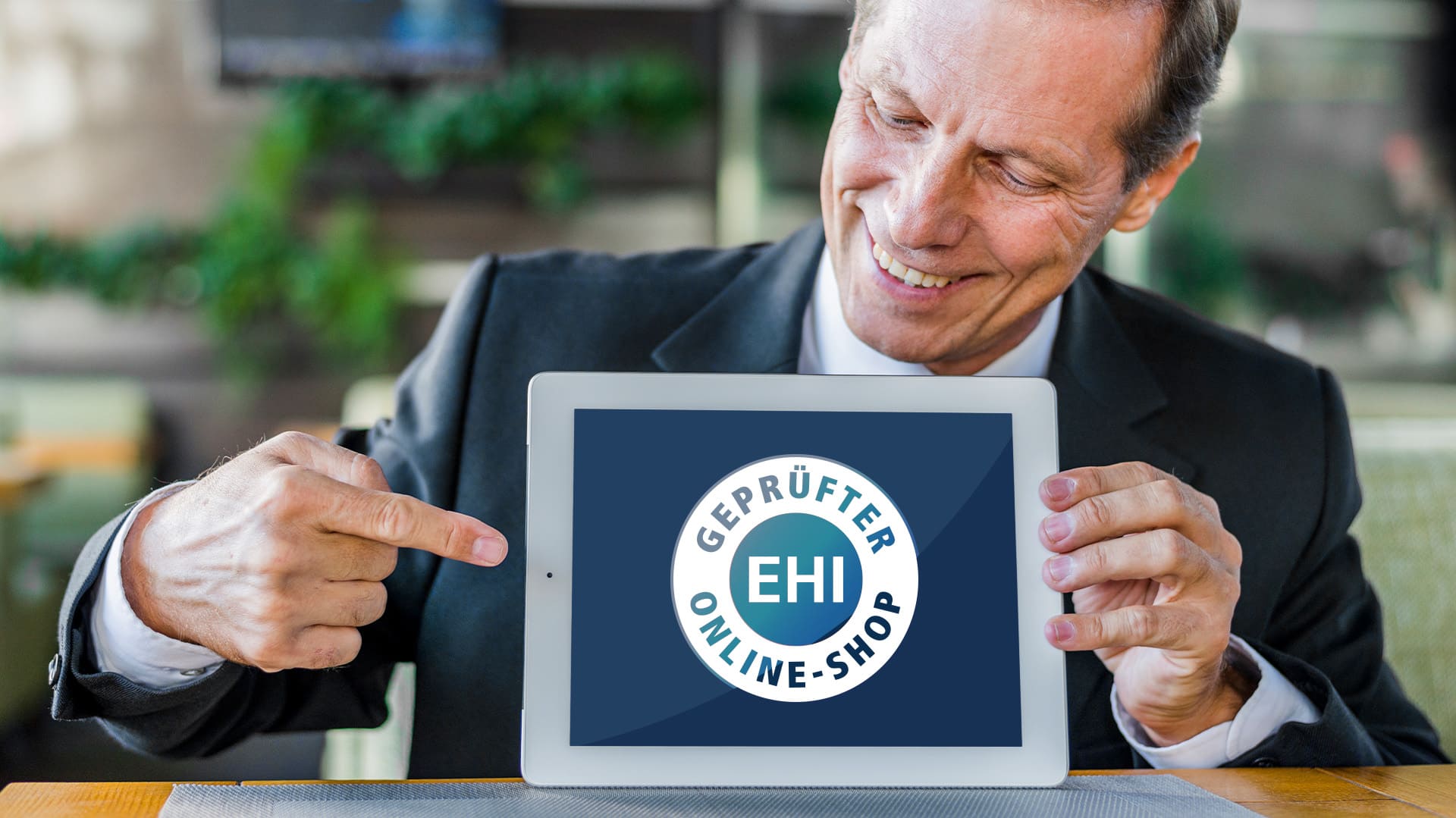 Ein Mann zeigt mit seinem Finger auf ein iPad, auf welchem das EHI - geprüfter Online-Shop-Siegel abgebildet ist Ein Mann zeigt mit seinem Finger auf ein iPad, auf welchem das EHI - geprüfter Online-Shop-Siegel abgebildet ist